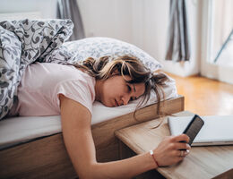 A woman looks at her phone in bed
